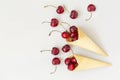 Ice cream cone filled with cherries on a grey light background. Fresh cherry in a waffle cone. Summer concept. Royalty Free Stock Photo