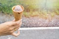 Ice cream cone filled with twirled softserve in hand / public park background