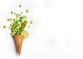 Ice cream cone flat lay image with green candy and kiwifruit spilling out of cone