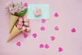 Ice cream cones with pink flowers and mint envelope on pink pastel background with heart shaped confetti Royalty Free Stock Photo