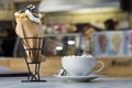 Ice cream dessert in wafer cup with chocolate cookies and and mug of coffee with marshmallows on porcelain plate on blurred Royalty Free Stock Photo