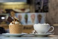 Ice cream dessert in wafer cup with chocolate cookies and and mug of coffee with marshmallows on porcelain plate on blurred Royalty Free Stock Photo