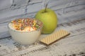 Ice cream in a glass bowl with decorative scattering, green apple and wafer, lie on a wooden table. Close-up