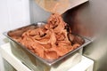 Ice cream making machine produces black chocolate ice cream flavors and it falls into steel container.