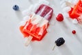 Homemade frozen blood red natural juice popsicles over ice with berries on marble background, top view Royalty Free Stock Photo