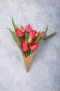 Ice cream of red  tulip flowers in waffle cone  on concrete  table top view in flat lay style Royalty Free Stock Photo