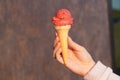 Ice cream red in waffle cone on bluer background. raspberry, strawberry or cherry frozen dessert, sorbet. girl holding cone of ice Royalty Free Stock Photo