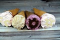 Ice-cream of special flavors in crispy wafer cones, melting cold ice cream twirl in a wafer biscuits on wooden background