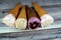 Ice-cream of special flavors in crispy wafer cones, melting cold ice cream twirl in a wafer biscuits on wooden background