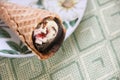 Ice cream stuffed with chocolate icing in a waffle cone on a plate