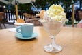 Ice cream sundae in a glass bowl and a coffee cup on the table in an outdoor cafe, delicious sweet dessert and refreshment in Royalty Free Stock Photo