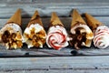 Ice cream vanilla and chocolate cones with topping of chocolate and caramel sauce and nuts in a crispy wafer cones, melting cold
