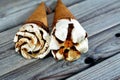 Ice cream vanilla cones with topping of chocolate and caramel sauce and nuts in a crispy wafer cones, selective focus of melting Royalty Free Stock Photo