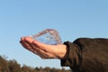 Ice crystal in a male hand against the blue sky