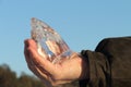 Ice crystal in a male hand against the blue sky