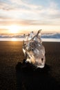 Ice crystal part piece iceberg glacial fragment on black sand ocean waves sunset Diamond Beach Jokulsarlon South Iceland