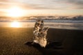 Ice crystal part piece iceberg glacial fragment on black sand ocean waves sunset Diamond Beach Jokulsarlon South Iceland