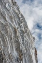 Ice crystals formed on rockface in winter against cloud sky