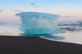 Ice cube on black volcano sand beach