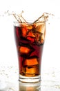 Ice cube droped in cola glass and cola splashing Royalty Free Stock Photo