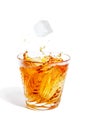 Ice cube falls with splashes into the glass with alcohol Royalty Free Stock Photo