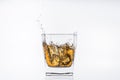 Ice cube falls with splashes into a glass with alcohol Royalty Free Stock Photo
