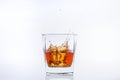 Ice cube falls with splashes into a glass with alcohol Royalty Free Stock Photo