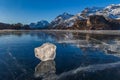 An ice cube with reflection on the frozen lake surface with ice cracks Royalty Free Stock Photo