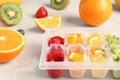 Ice cube tray with different fruits and berries on table Royalty Free Stock Photo