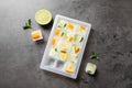 Ice cube tray with frozen fruits and mint on table, flat lay Royalty Free Stock Photo