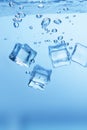 Ice cubes in blue water create bubbles that float to the surface Royalty Free Stock Photo