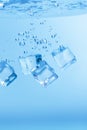 Ice cubes in blue water create bubbles that float to the surface Royalty Free Stock Photo