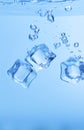 Ice cubes in blue water create bubbles that float to the surface Royalty Free Stock Photo