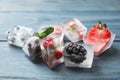 Ice cubes with different berries and mint on wooden table, closeup Royalty Free Stock Photo