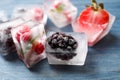 Ice cubes with different berries and mint on wooden table, closeup Royalty Free Stock Photo