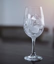 Ice cubes in an empty glass wine on a wooden bar counter, soft light background Royalty Free Stock Photo