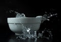 Ice cubes falling into white bowl on a black background stopped with high speed photography Royalty Free Stock Photo