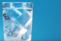 Ice cubes in a glass with crystal clear water on a blue background Royalty Free Stock Photo