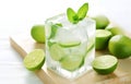 ice cubes, mint herb and fresh lime slices in glass on white wooden table