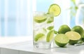 ice cubes, mint herb and fresh lime slices in glass on white wooden table