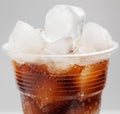 Ice cubes in a plastic cup with a drink cola on gray background Royalty Free Stock Photo