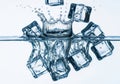 Ice cubes splash into clear water creating ripples and reflections Royalty Free Stock Photo