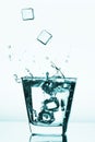 Ice cubes splashing into glass, ice cube dropped into glass of water Royalty Free Stock Photo