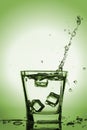 Ice cubes splashing into glass, ice cube dropped into glass of water Royalty Free Stock Photo