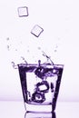 Ice cubes splashing into glass, ice cube dropped into glass of water Royalty Free Stock Photo