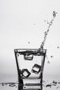 Ice cubes splashing into glass, ice cube dropped into glass of water Royalty Free Stock Photo