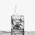 Ice cubes splashing into glass of water closeup, isolated on white Royalty Free Stock Photo