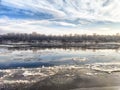 Ice drift on the river during spring reveals melting winter landscape with reflections of trees and clouds Royalty Free Stock Photo