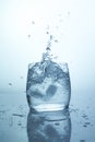 Ice falling from a takan of water, a splash of ice cube with splashes, pure drinking water in a transparent glass Royalty Free Stock Photo