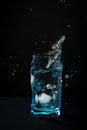 Ice falls into the glass. splash of frozen water. Blue beautiful wine glass Royalty Free Stock Photo